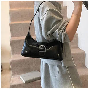 Close-up of black glossy crescent bag with silver D-buckle and rivet details
