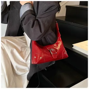 Detail of red patent leather crescent bag with silver buckles and stud decorations