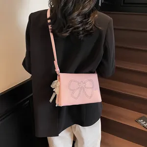 Pink crossbody bag with silver stud bow design and pearl lace charm shown on a model