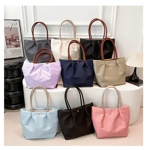 Close-up of minimalist nylon tote bags in nine colors with pleated design and leather handles