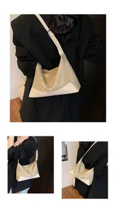Detailed view of cream canvas crescent bag with leather trim and adjustable strap