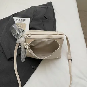 Elegant beige crossbody flap bag with pearl lace charm and smooth faux leather finish