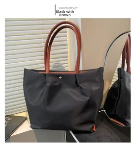 Detail of nylon tote bag in black and brown with metal snap button and leather strap