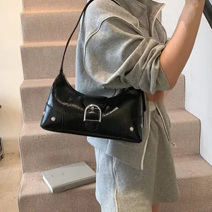 Fashionable black patent leather crescent shoulder bag with silver D-buckle and metal rivets