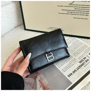 Close-up of black retro textured leather wallet featuring a silver metal letter B buckle