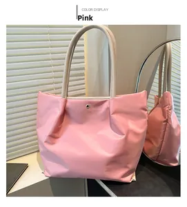 Detailed close-up of pink nylon tote bag with beige leather handles and gold metal snap button