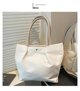 Detail of white nylon tote bag featuring durable handles and metal rivet decoration
