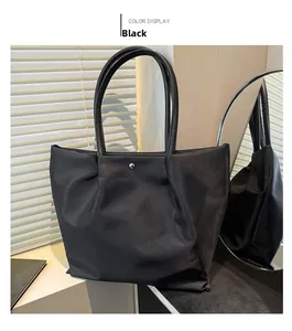 Close-up of black nylon tote bag with leather handles and metallic button detail