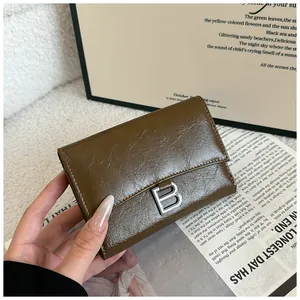 Detailed close-up of dark brown textured leather wallet with silver B logo metal clasp