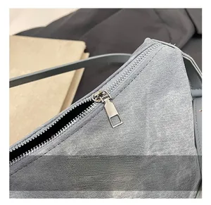 Detailed macro shot of silver metal zipper and denim fabric texture on the shoulder bag