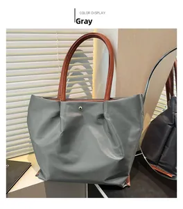 Detail of grey waterproof nylon tote bag featuring brown handles and metal snap closure