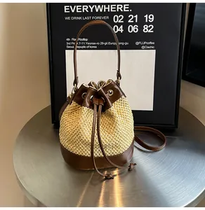 Detail of woven straw bucket bag with dark brown leather trim and drawstring closure