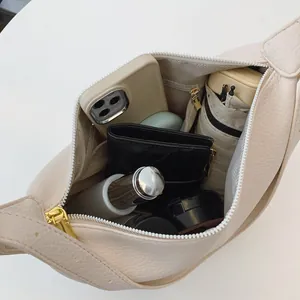 Sac hobo demi-lune chic en cuir beige montrant une grande capacité et un rangement interne
