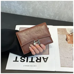 Detail view of brown vintage leather wallet with metal B buckle and magnetic closure