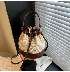 Detail of woven straw bucket bag with brown leather trim and drawstring closure