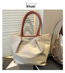 Detail view of khaki nylon tote bag with brown handles and snap button closure