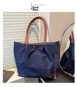 Detailed view of dark blue nylon tote bag with brown leather handles and silver snap closure