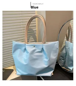 Detail of blue waterproof nylon tote with golden snap button and khaki leather handles