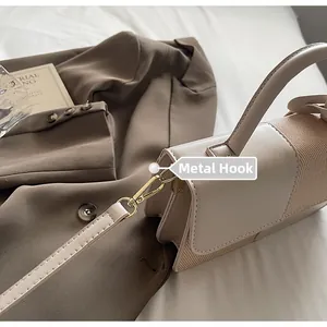 Detail of high-gloss gold metal hook and detachable strap on beige leather shoulder bag