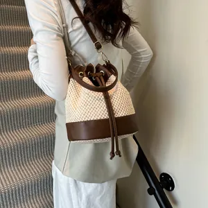 Chic woven bucket bag with brown leather trim shown in a stylish side-carry view
