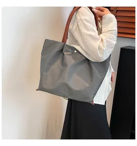 Detail of grey nylon tote bag with brown leather handle and gold buckle closure