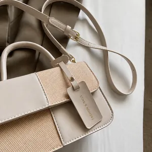 Detail of contrast stitching and woven texture on handbag with a fashion hangtag accessory