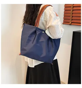 Detail of dark blue waterproof nylon tote bag with brown leather straps on shoulder