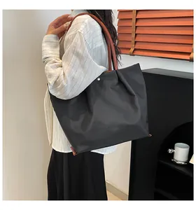 Detail of waterproof nylon tote bag with durable leather handles and gold metal hardware