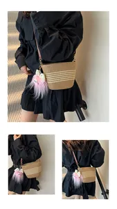Détail d'un sac seau en paille tissée avec rayures blanches et breloque monstre rose
