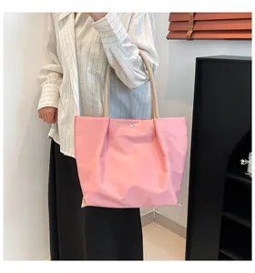 Detailed side view of a light pink nylon tote bag with beige straps on model