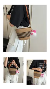 Détail du sac seau en paille tressée avec rayures noires et breloque pelucheuse