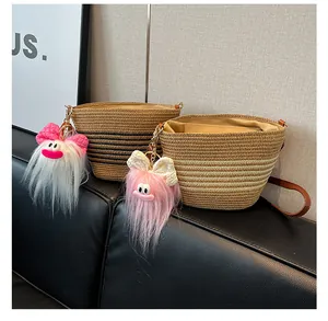 Vue détaillée des sacs seaux en paille tissée avec garniture en cuir et charmes en peluche