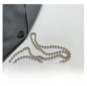 Detail of silver metallic beaded chain strap on grey blazer for a modern fashion look