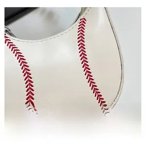 Macro view of white leather handbag with red V-shaped stitching detail mimicking baseball seams