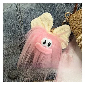 Détail d'un charm en peluche rose avec nœud crème sur un sac seau en paille tressée