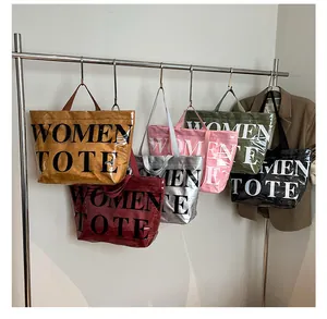 Dettaglio di borse tote eleganti in vari colori con trama plissettata e stampa di lettere grandi