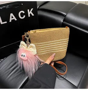 Détail d'un sac seau en paille tressée avec bandoulière cuir et charme en peluche