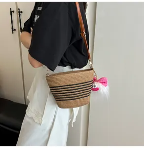 Détail du sac seau en paille tissée avec rayures noires et breloque monstre en peluche