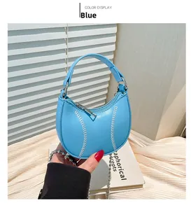 Detail of light blue crescent mini bag with baseball style stitching and chain strap