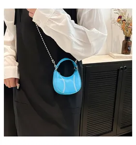 Detail of bright blue mini crescent bag with baseball stitch and silver bead chain