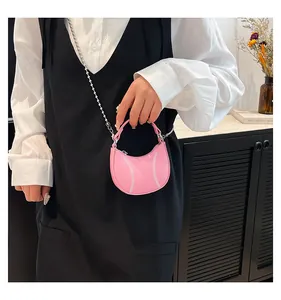 Detail of pink crescent bag with white baseball stitching and silver chain strap