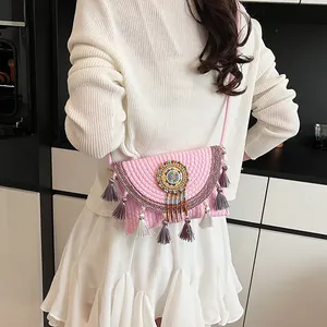 Bohemian woven crossbody bag with pink stripes, ethnic beadwork, and tassels on a model