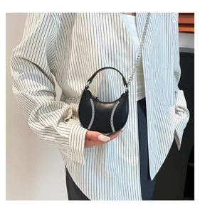 Close-up of black leather dumpling bag featuring white baseball stitching and silver chain