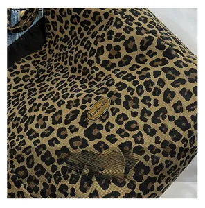 Detail of leopard print canvas fabric with a bronze handmade metal logo plate