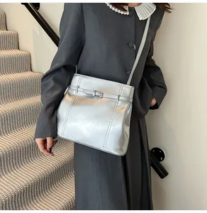 Detalle de bolso de hombro en PU plateado con hebilla decorativa en una modelo femenina