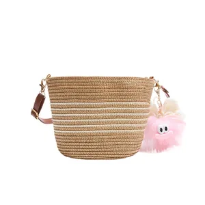 Sac seau en paille rayé avec bandoulière en cuir marron et breloque monstre rose
