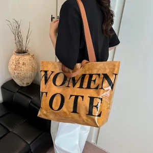 Grande borsa tote trasparente in PVC marrone con scritta e tracolla lunga da donna