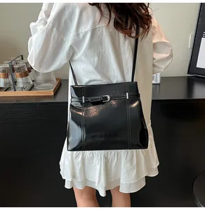 Vista de detalle de bolso tipo cubo en cuero PU negro brillante con hebilla plateada