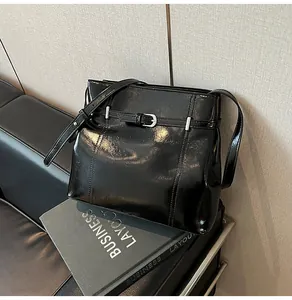 Detalle del bolso de cubo en cuero PU negro brillante con hebillas metálicas plateadas