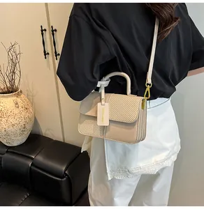 Dettaglio delle texture a contrasto e hardware dorato sulla borsa a tracolla bianco crema